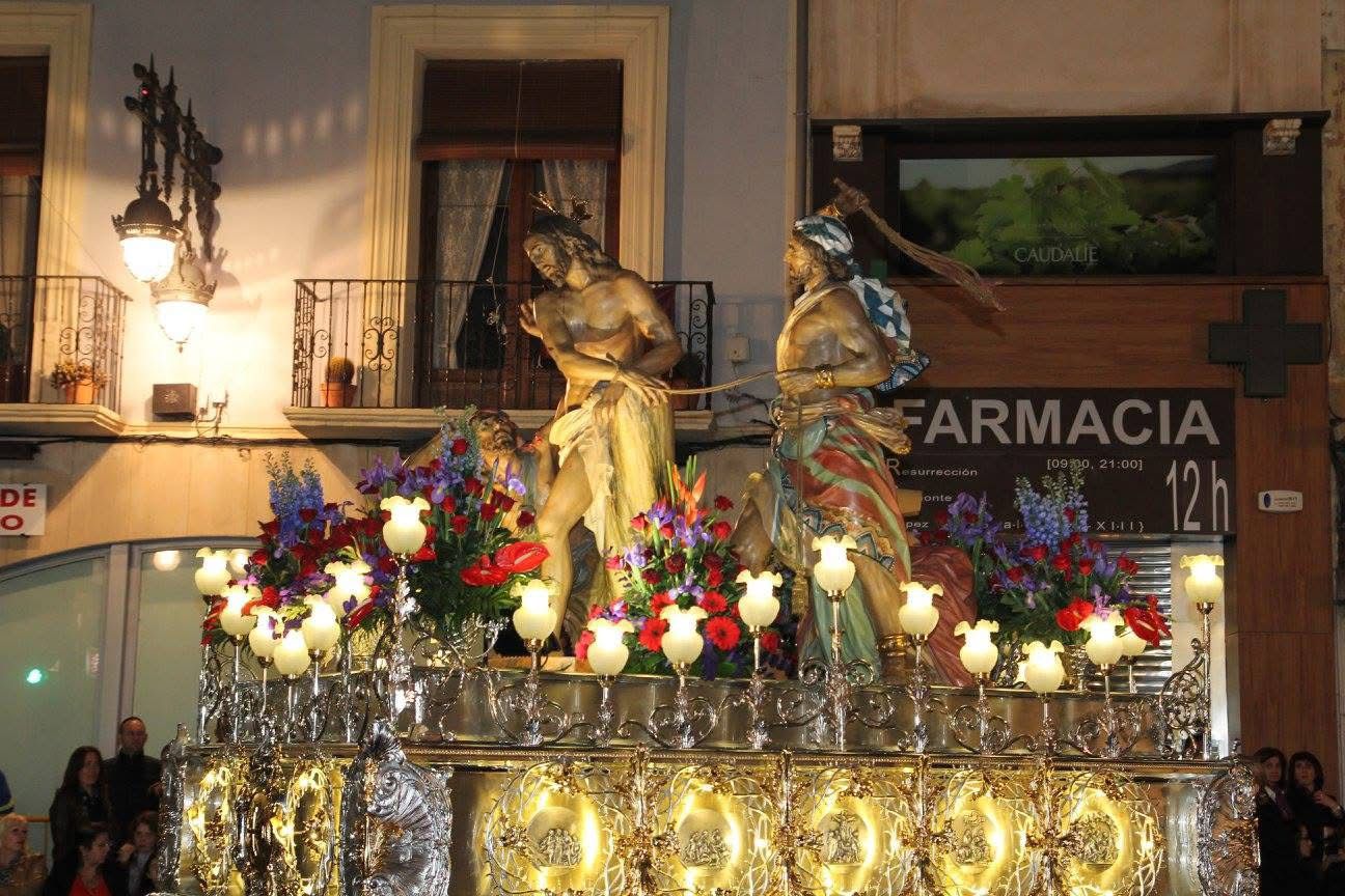 El paso de La Flagelación procesionando de noche por las calles de Orihuela, sobre su trono de plata y entre flores y cirios.